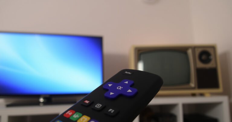 A close-up of a Roku remote with colorful buttons, set against a backdrop of two contrasting televisions: one sleek modern flat-screen and one vintage box TV. Soft ambient lighting highlights the remote’s features, while a faint glow emanates from the screens, hinting at the potential of connecting with different devices.